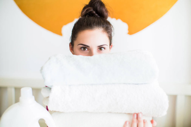 Close-up half of the young woman's face behind the folded towels in the room - 写真・画像