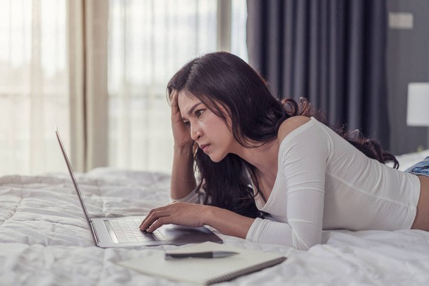 stressed woman using a laptop computer on bed - Photo, image