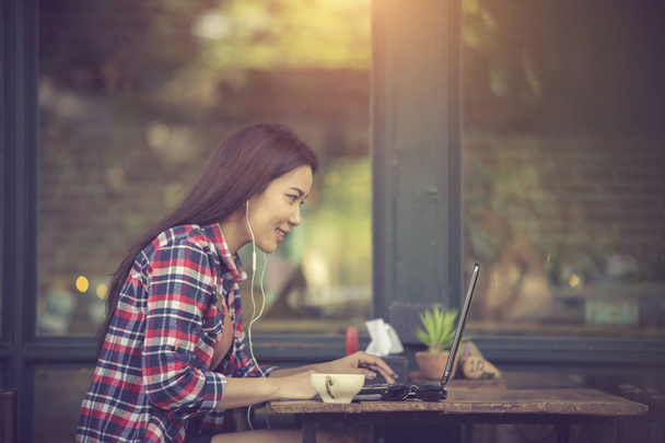 Skoncentrowany w pracy. Pewna siebie młoda kobieta w eleganckim, luźnym ubraniu pracująca na laptopie siedząc przy oknie w kreatywnym biurze lub kawiarni - Zdjęcie, obraz