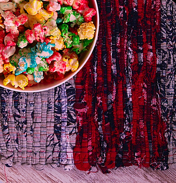 overhead foto van gekleurde popcorn in een kom, over een ontwerp van de gekleurde pad met rode lijnen - Foto, afbeelding