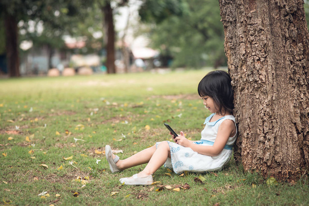 little girl with a mobile phone in the park - Fotografie, Obrázek