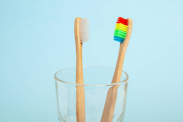 Σύνολο οδοντόβουρτσες σε γυαλί σε μπλε φόντο. Οδοντόβουρτσα επιλογής έννοιας, μπαμπού φιλικό προς το περιβάλλον. Έννοια της ΛΟΑΤ Κοινότητας και σεξουαλικών μειονοτήτων - Φωτογραφία, εικόνα