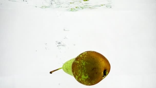 Ζουμερό πράσινο αχλάδι σε απομονωμένες άσπρο φόντο σε αργή κίνηση. Συνέδριο αχλάδι είναι βυθισμένο στο νερό με φυσαλίδες. - Πλάνα, βίντεο
