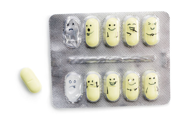 balení tablet s žlutým práškům a malované emoce izolovaných na bílém pozadí. - Fotografie, Obrázek