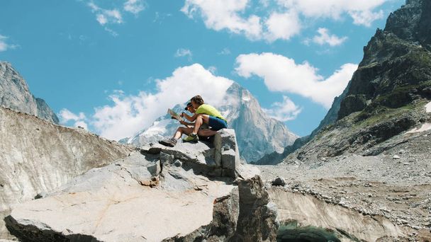 Para turystów siedzieć na skale i studiować mapę papierową, planowania trasy w górskie wycieczki. - Zdjęcie, obraz