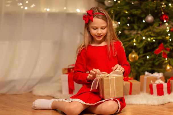 smiling girl with christmas gift at home - Foto, afbeelding