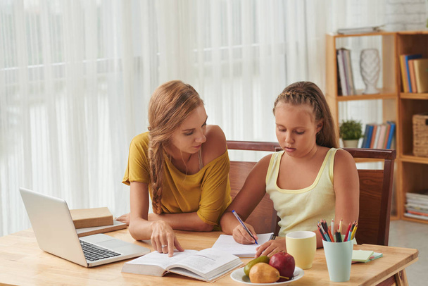 beyaz anne ve kızı masada kitap, ders kitabı yazım kalemi ile öğrenci kız ile ev görev yapıyor  - Fotoğraf, Görsel