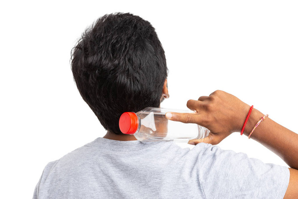 Mann aus Indien berühren Hals mit Kunststoff-Wasserflasche mit dem Rücken zur Kamera isoliert auf weißem Hintergrund als bleiben hydratisiertes Konzept - Foto, Bild