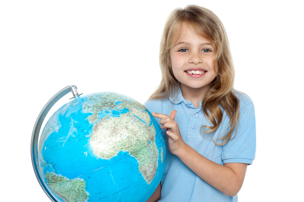 Pretty school child holding globe and pointing - Photo, Image