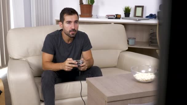 Adult man plays a video game on the console in the living room - Záběry, video