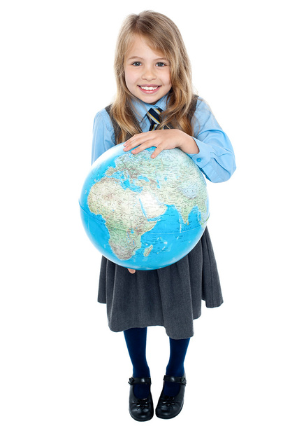 Pretty school child holding globe and pointing - Foto, Bild