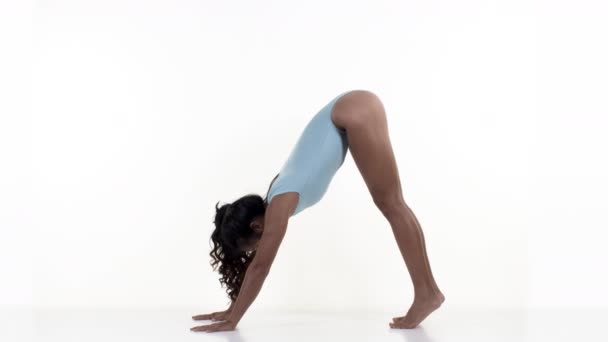 Γυναίκα κάνει διατάσεις και γυμναστικές ασκήσεις σε λευκό φόντο - Πλάνα, βίντεο