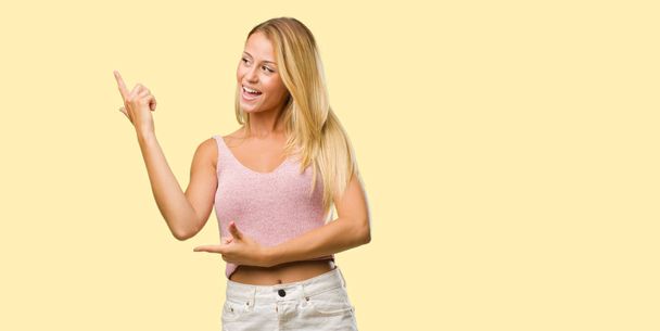 Portrait of young pretty blonde woman pointing to side - Photo, Image