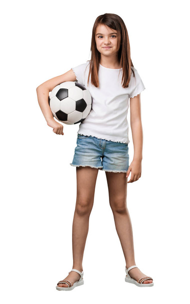 Полное тело маленькая девочка улыбается и счастлива, держа в руках футбольный мяч, соревновательное отношение, с удовольствием играет в игру
 - Фото, изображение