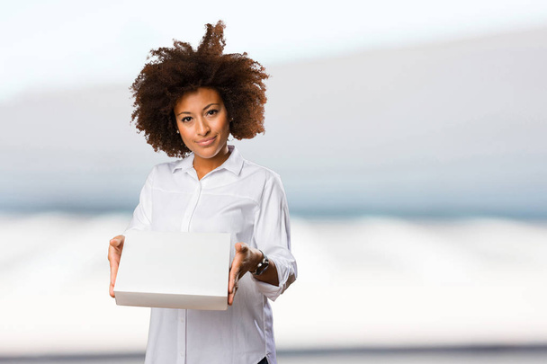 young black woman holding a white box on blurred background - Fotoğraf, Görsel