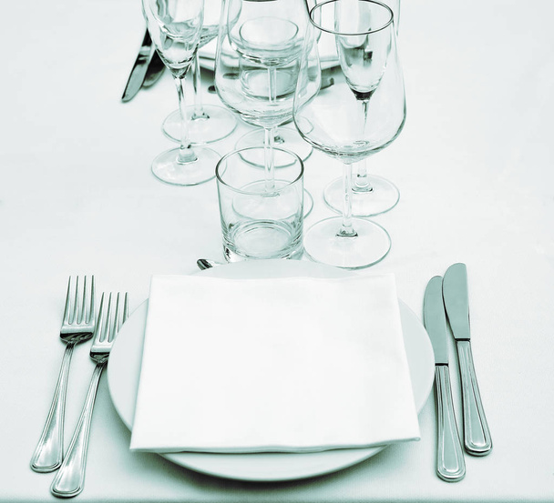 Assiette, verres vides, serviette blanche, fourchettes et couteaux sur nappe blanche (effet vert
) - Photo, image