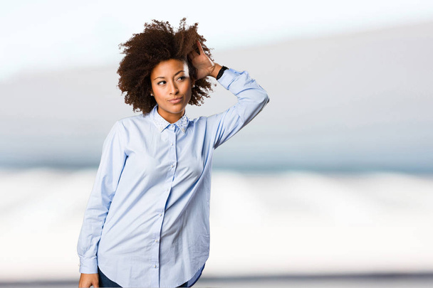 Młoda kobieta czarny w niebieska koszula nasłuchuje na niewyraźne tło - Zdjęcie, obraz