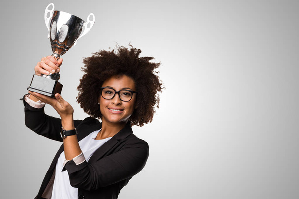 black business woman holding a trophy on gray background - Photo, Image