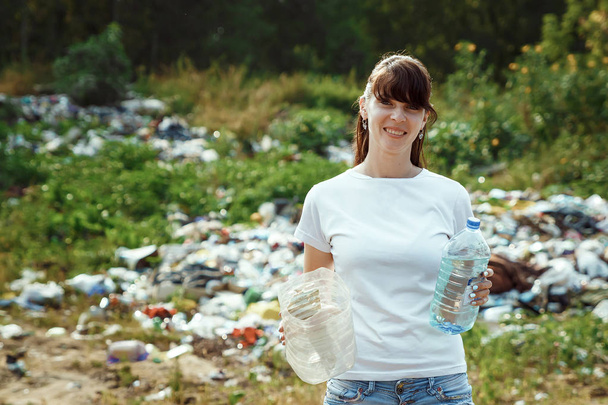 Volunteers collect garbage in the wild. An energetic girl-volunteer, collects garbage. The concept of garbage collection, volunteering. - Foto, Bild