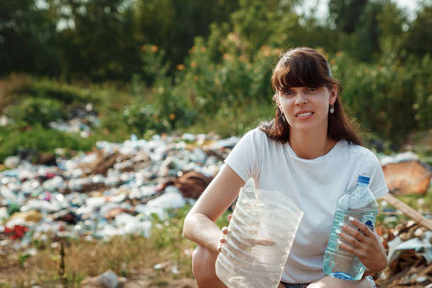 Los voluntarios recogen basura en la naturaleza. Una muchacha-voluntaria enérgica, recoge basura. El concepto de recolección de basura, voluntariado
. - Foto, imagen
