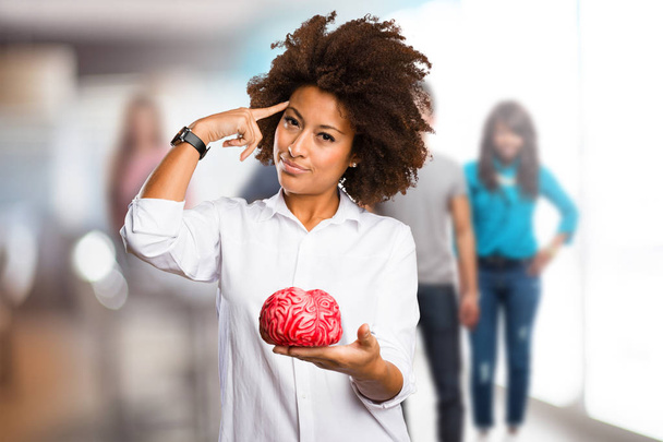 молодая черная женщина держит мозг формы с размытыми людьми в фоновом режиме
 - Фото, изображение