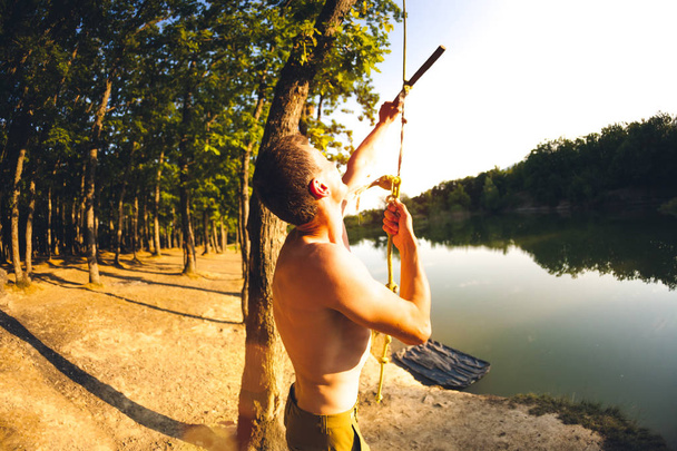 Skok z zítřejšímu seskoku. Člověk odpočívá na jezeře. Swing lano a klacek. Aktivní odpočinek v přírodě. Letní zábavy. Objektiv s rybím okem. - Fotografie, Obrázek
