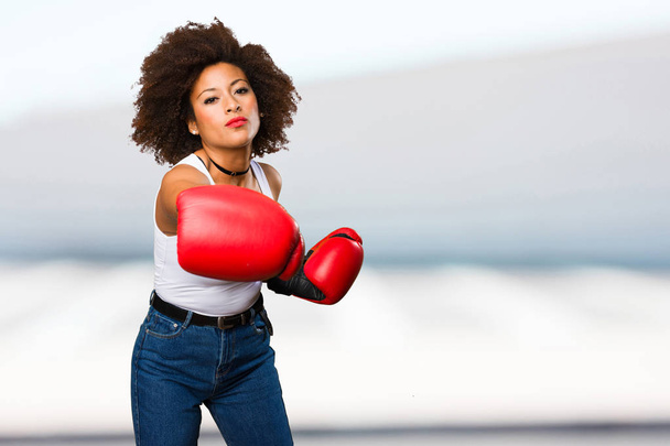 nuori musta nainen käyttää nyrkkeilyhanskat hämärtynyt tausta
 - Valokuva, kuva