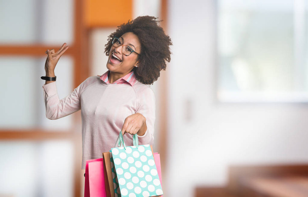 mulher negra segurando sacos de compras
 - Foto, Imagem
