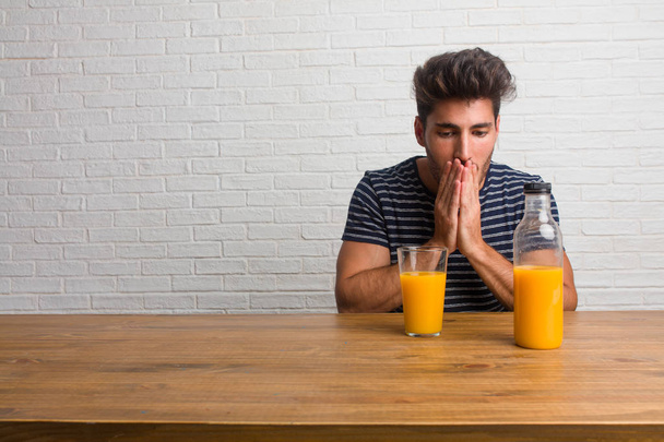Természetes és jóképű fiatalember ül egy asztal, száj, szimbólum, a csend és az elnyomás, amely nem próbál mondani valamit. A reggeli elfogyasztására, magában foglalja a narancs juice és a gabonafélék tál. - Fotó, kép