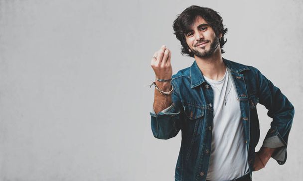 Joven hombre guapo haciendo un gesto típico italiano, sonriendo y mirando hacia adelante, símbolo o expresión con la mano, muy natural
 - Foto, Imagen
