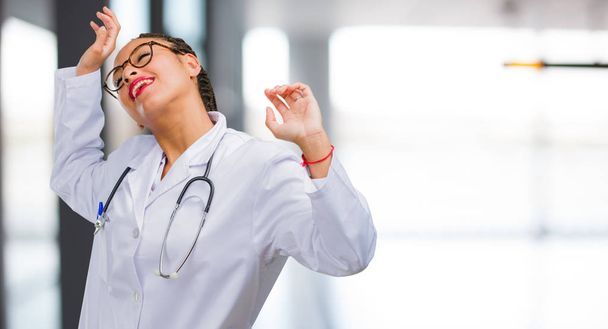Portrait of a young black doctor woman Listening to music, dancing and having fun, moving, shouting and expressing happiness, freedom concept - Foto, Imagem
