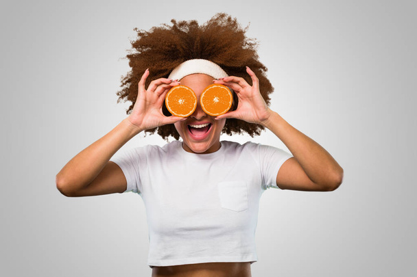 νέοι γυμναστήριο Αφρο γυναίκα κρατώντας ένα πορτοκάλι - Φωτογραφία, εικόνα