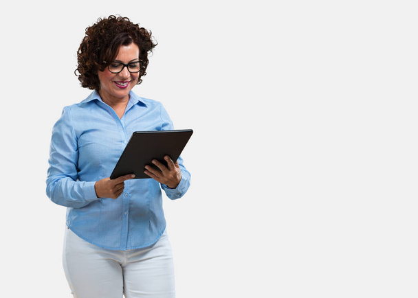 Femme d'âge moyen souriante et confiante, tenant une tablette, l'utilisant pour surfer sur Internet et voir les réseaux sociaux, concept de communication
 - Photo, image
