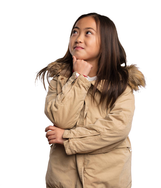 白い背景で隔離のベージュ ジャケット思考の中国少女 - 写真・画像