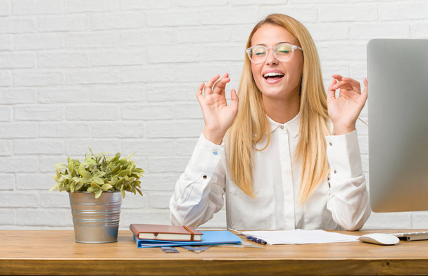 Portrait of young student sitting on her desk doing tasks laughing and having fun, being relaxed and cheerful, feels confident and successful - Photo, Image