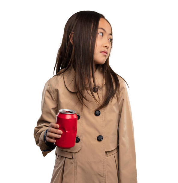 κινεζική κοριτσάκι σε μπεζ trenchcoat κρατώντας ένα ποτό σόδα που απομονώνονται σε λευκό φόντο - Φωτογραφία, εικόνα