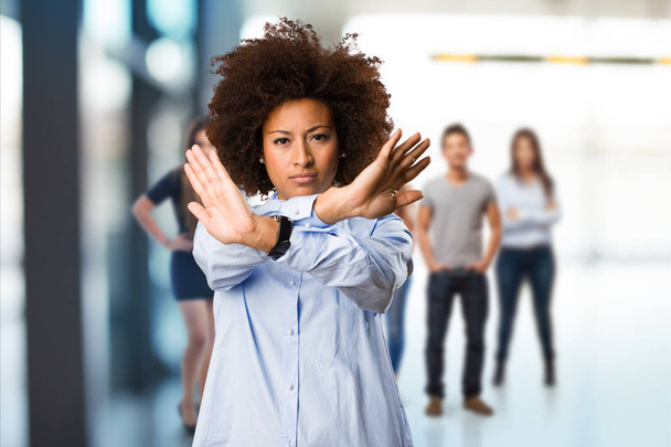 jonge zwarte vrouw doen stop gebaar met wazig mensen op achtergrond - Foto, afbeelding