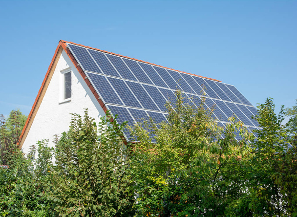Casa moderna con células solares fotovoltaicas en el techo para la producción de energía alternativa - Foto, imagen