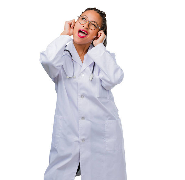Προσωπογραφία γυναίκας νεαρό μαύρο γιατρό που καλύπτουν τα αυτιά με τα χέρια, θυμωμένος και κουρασμένος από ακρόαση κάποιο ήχο - Φωτογραφία, εικόνα