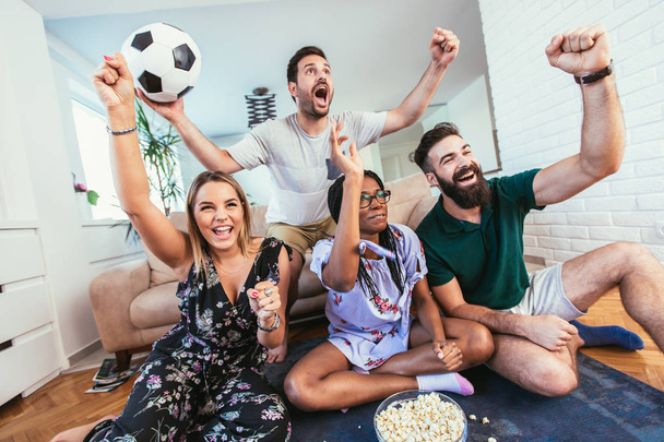 Gelukkige vrienden of voetbalfans die voetbal kijken op tv en thuis de overwinning vieren.Vriendschap, sport en entertainment concept. - Foto, afbeelding