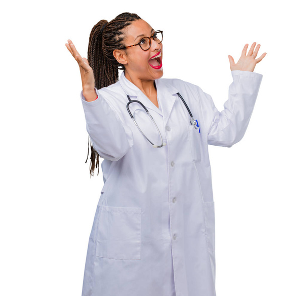 Muotokuva nuori musta lääkäri nainen huutaa onnellinen, yllättynyt tarjouksen tai edistäminen, ammottava, hyppääminen ja ylpeä
 - Valokuva, kuva