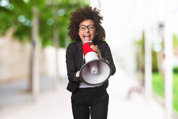 zwarte zakenvrouw schreeuwen op de megafoon op onscherpe achtergrond - Foto, afbeelding