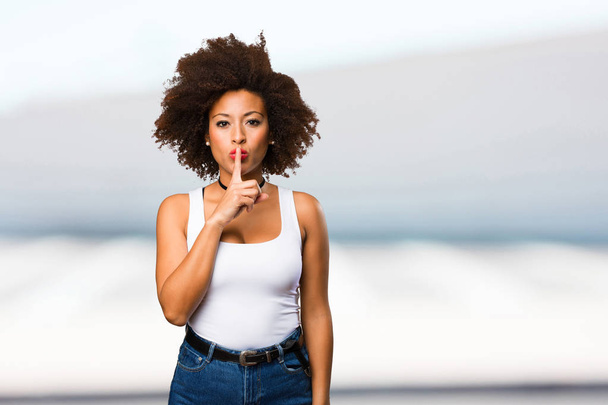 giovane donna nera fare silenzio gesto su sfondo sfocato
 - Foto, immagini