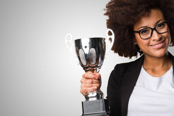black business woman holding a trophy on gray background - Photo, Image