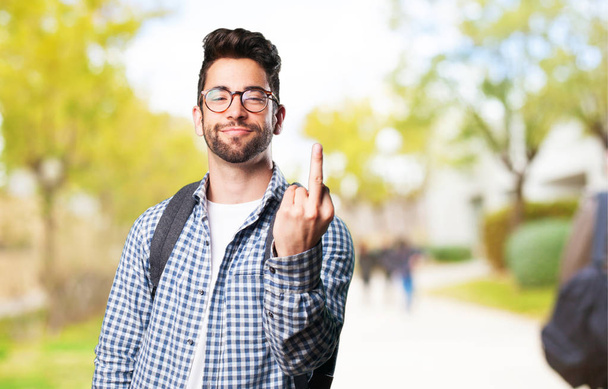 молодий чоловік ображається середнім пальцем на розмитому фоні
 - Фото, зображення