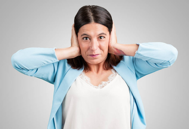 Жінка середнього віку, що покриває вуха руками, сердита і втомилася чути якийсь звук
 - Фото, зображення