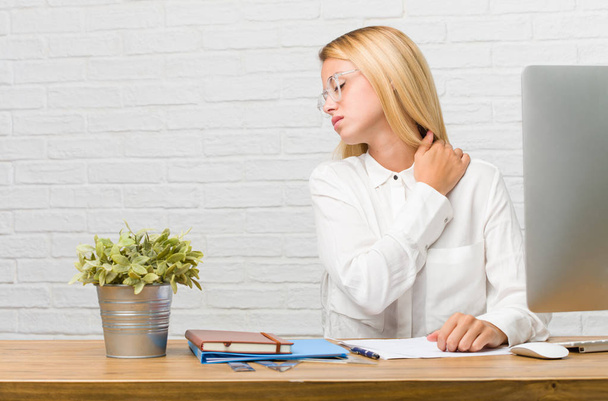 Portrait d'une jeune étudiante assise sur son bureau faisant des tâches avec des maux de dos dus au stress au travail, fatiguée et astucieuse
 - Photo, image
