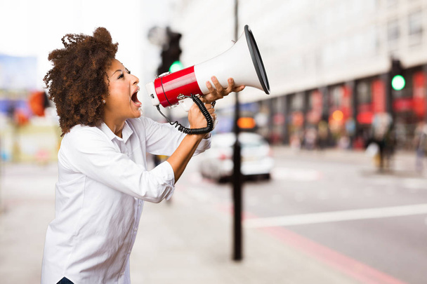 joven mujer negra gritando en megáfono sobre fondo borroso
 - Foto, imagen