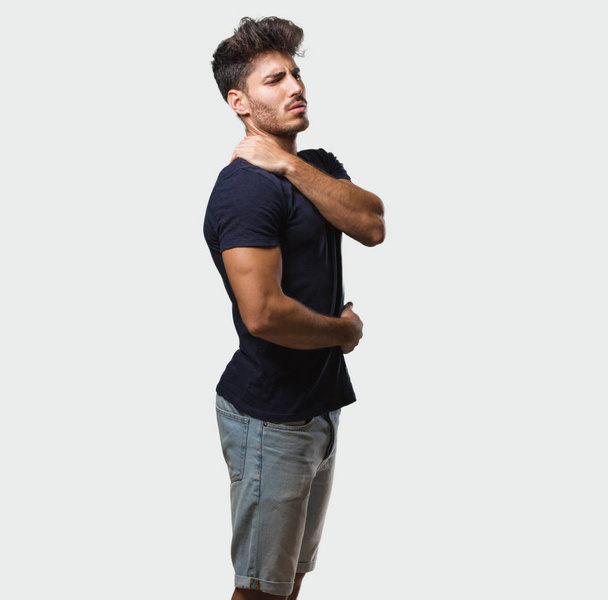 Young handsome man standing with back pain due to work stress, tired and astute - Фото, изображение