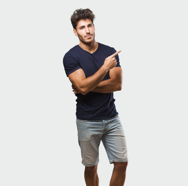 Young handsome man standing pointing to the side, smiling surprised presenting something, natural and casual - Fotoğraf, Görsel